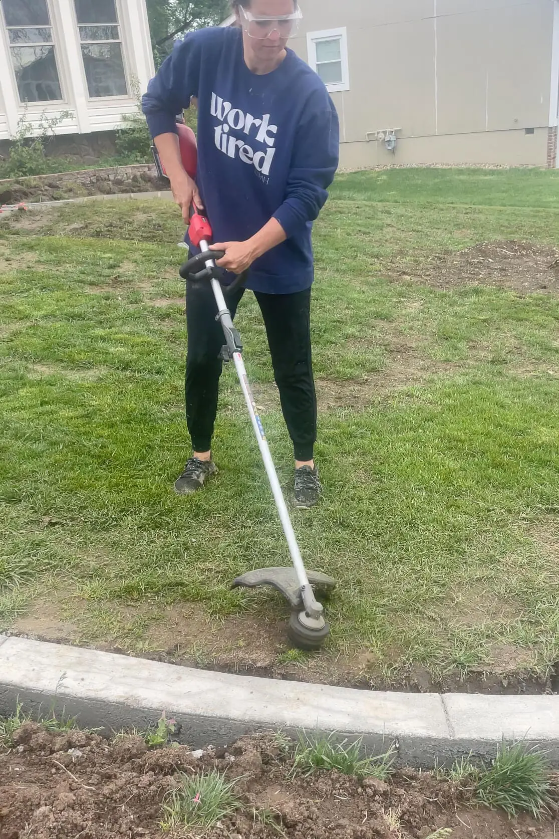 Removing grass with a weed eater in order to prepare for laying sod.